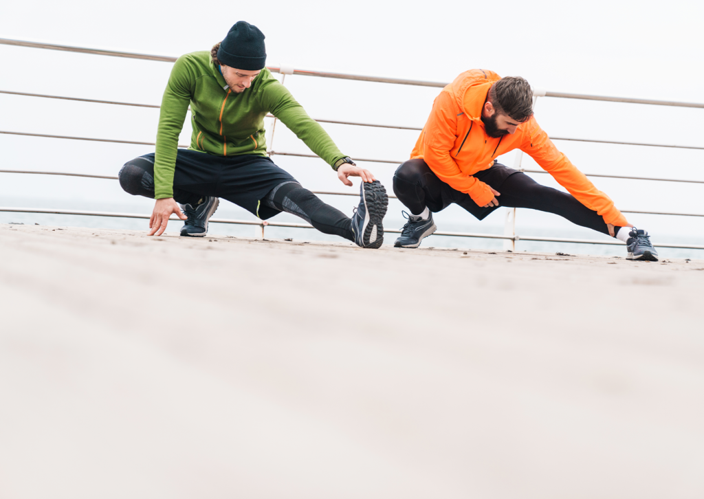 Un par de amigos haciendo estiramientos para calentar el cuerpo durante el invierno.