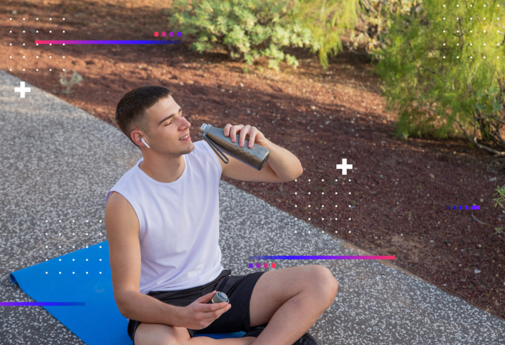 Un hombre se detiene para tomar un trago de agua de su botella mientras hace ejercicio en el gimnasio, sabiendo que la hidratación es clave para mantenerse energizado y evitar la deshidratación.